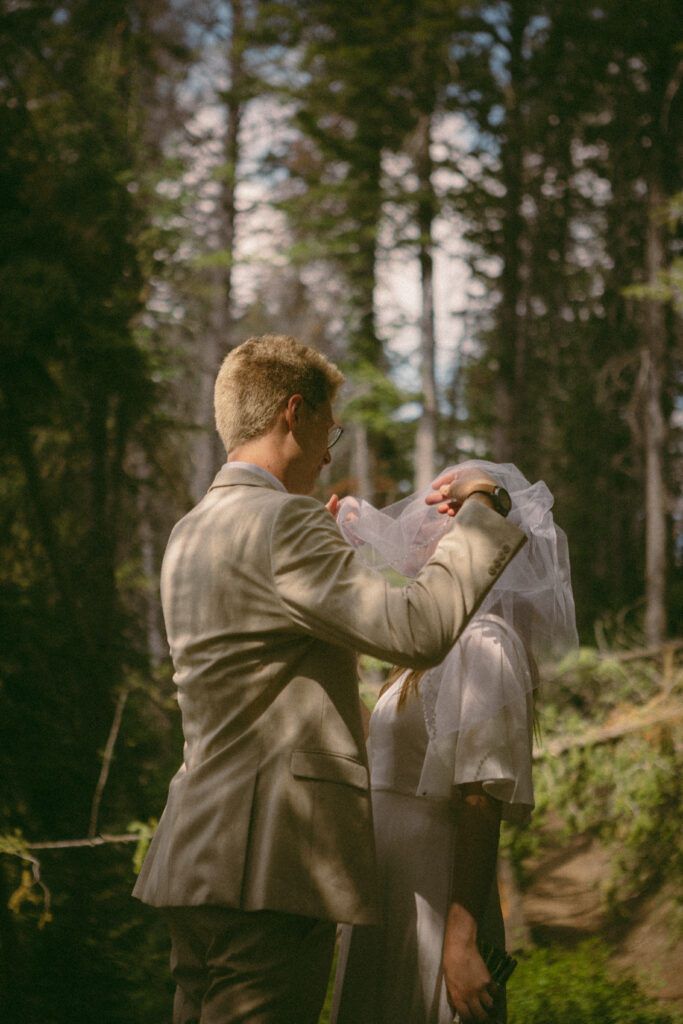 groom pulls back brides veil and gives her a kiss