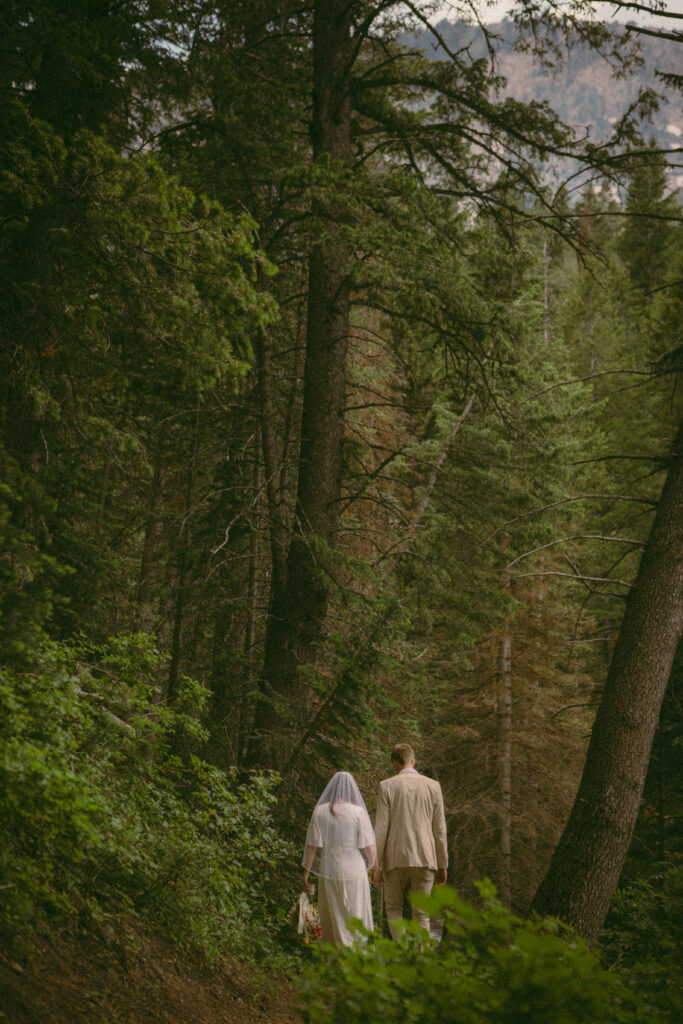 bride and groom walking through the forest