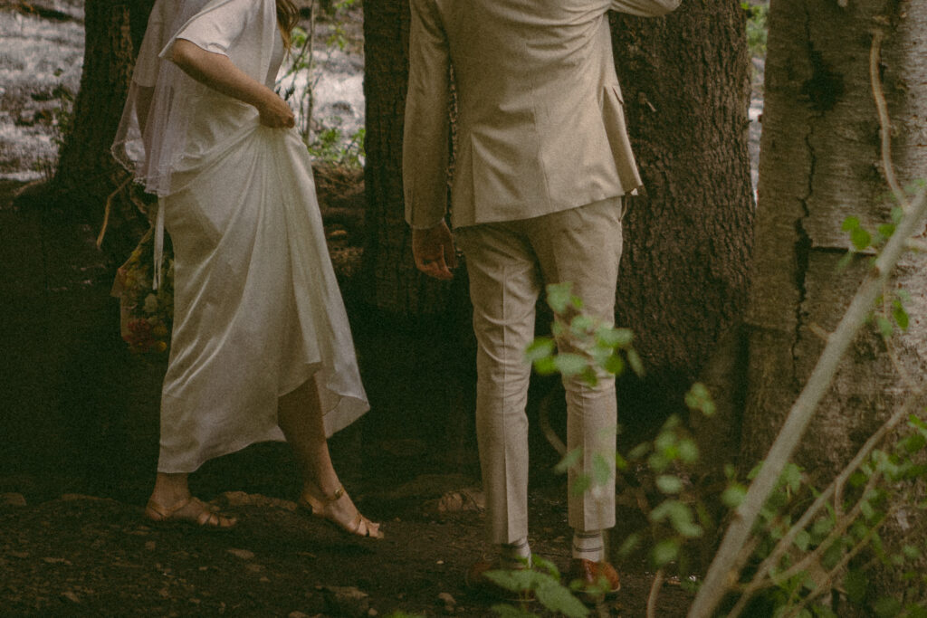 bride and groom walk across bridge over water