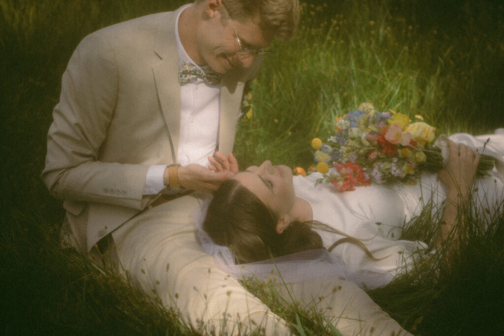 cinematic photo of bride and groom lying in a field