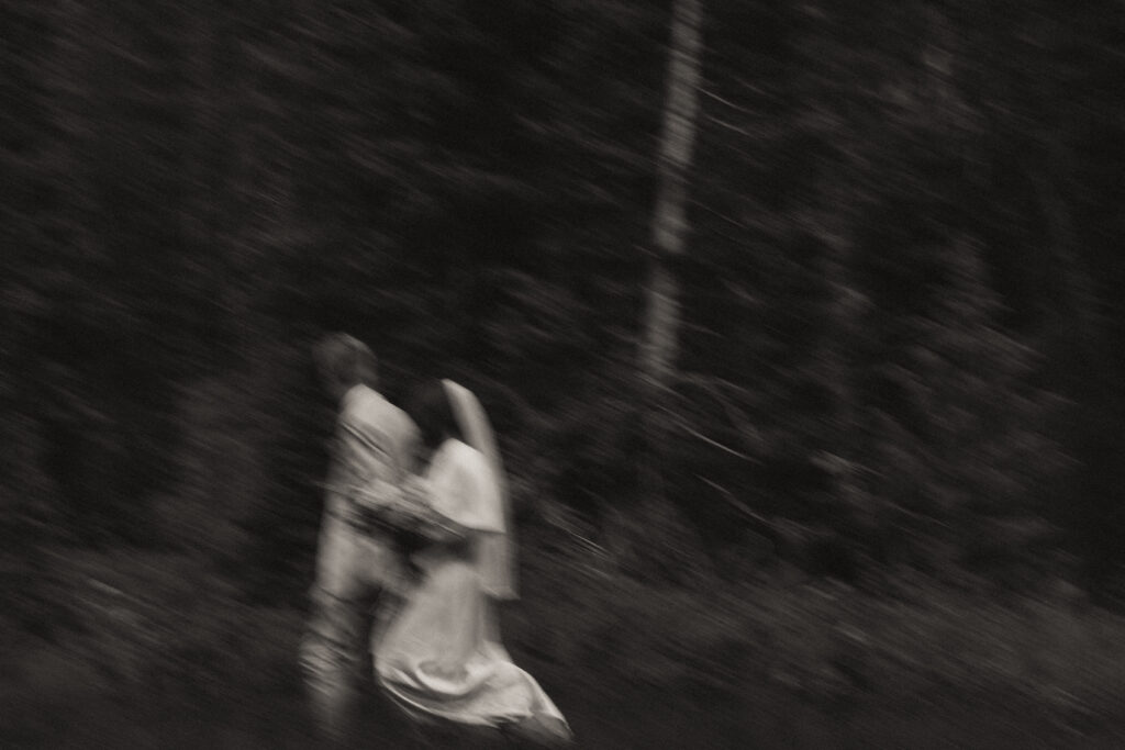bride and groom walk through the forest black and white