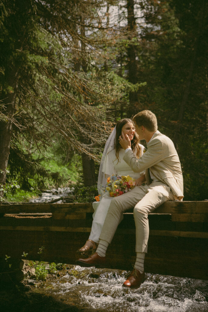bride and groom sitting together on a bridge