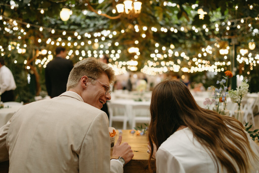 couple talks to each other and laughs at the head table looking over the reception hall