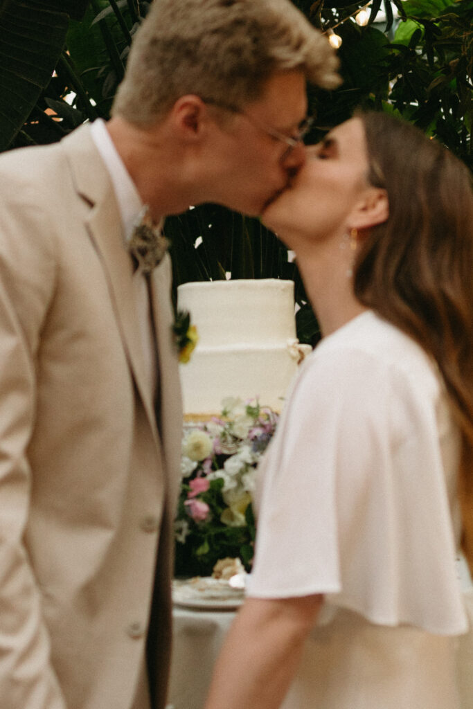 bride and groom kiss after cutting their wedding cake