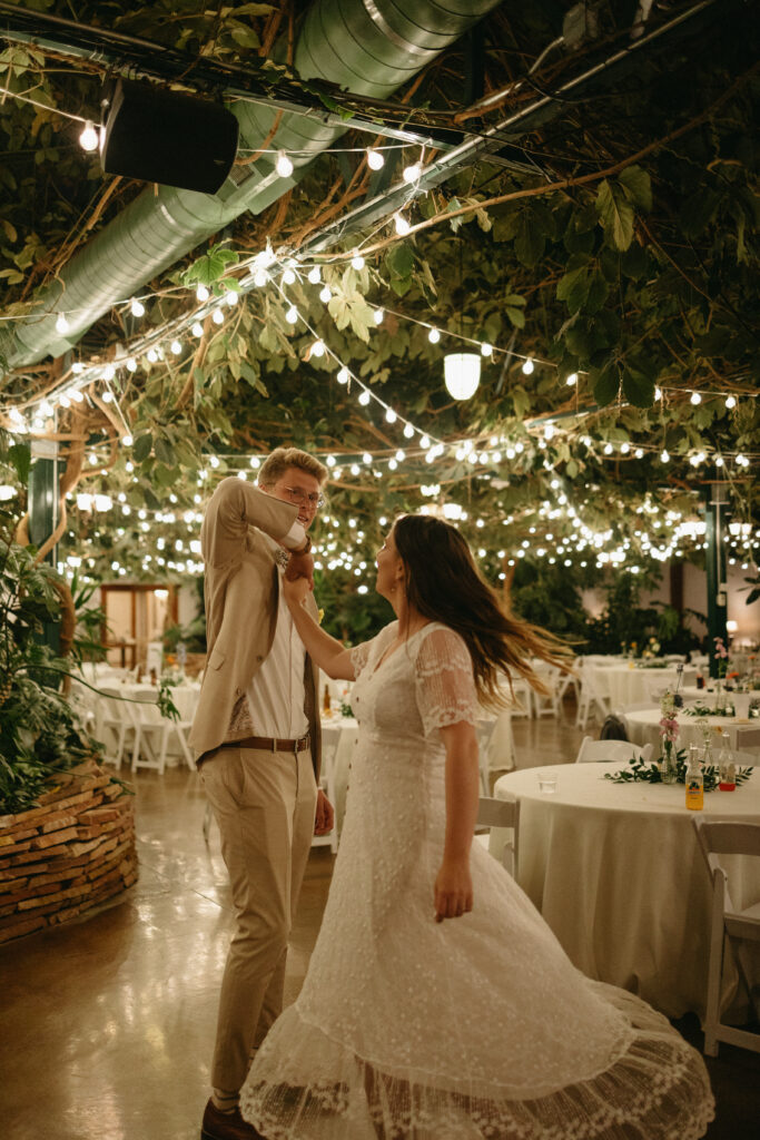 couple spinning in their wedding dress, garden fairy lights behind them 