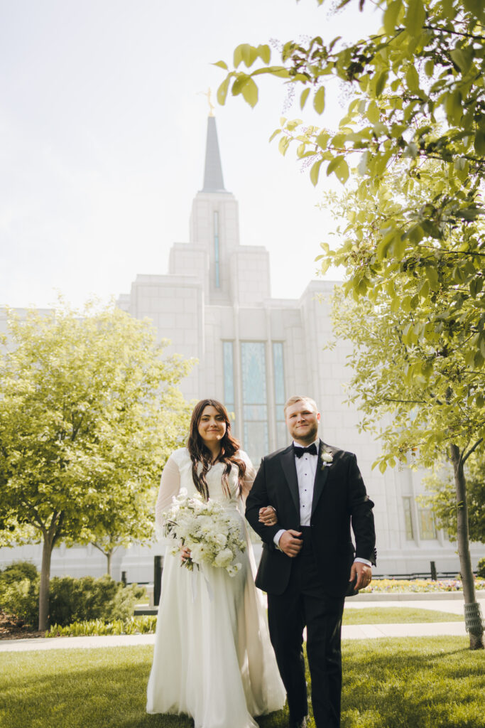 bride and groom standing in front of temple after wedding ceremony