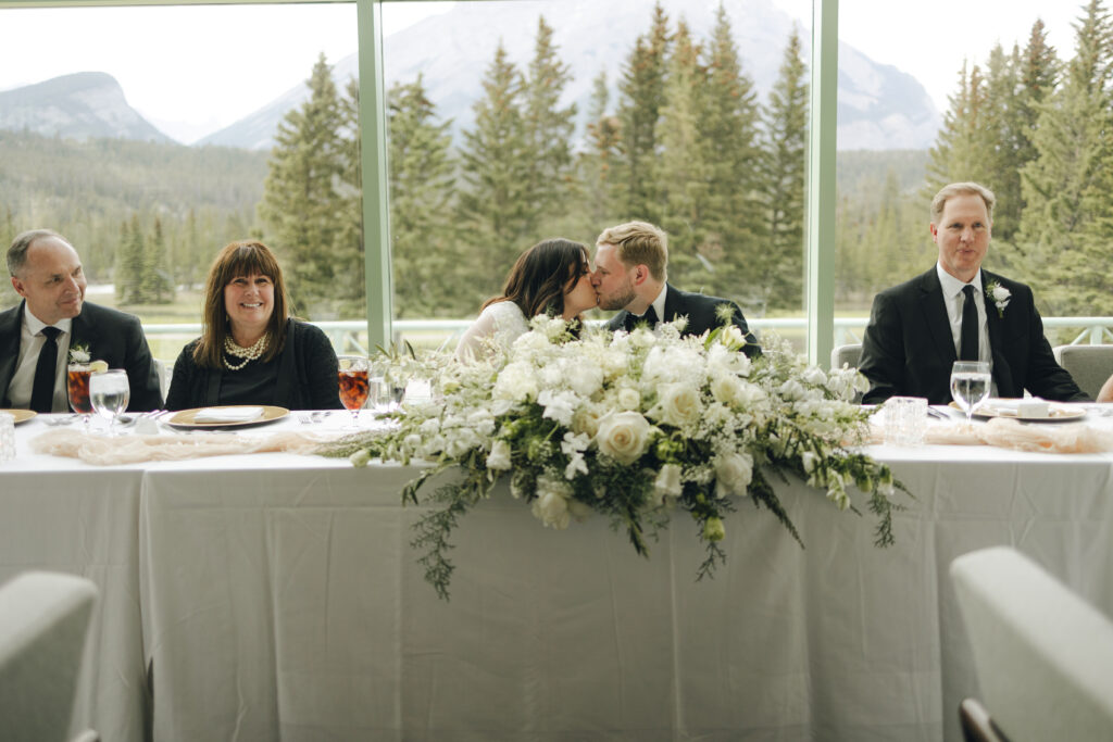 bride and groom kiss at the wedding table