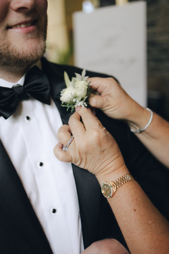mother of the groom helping pin on his boutonniere